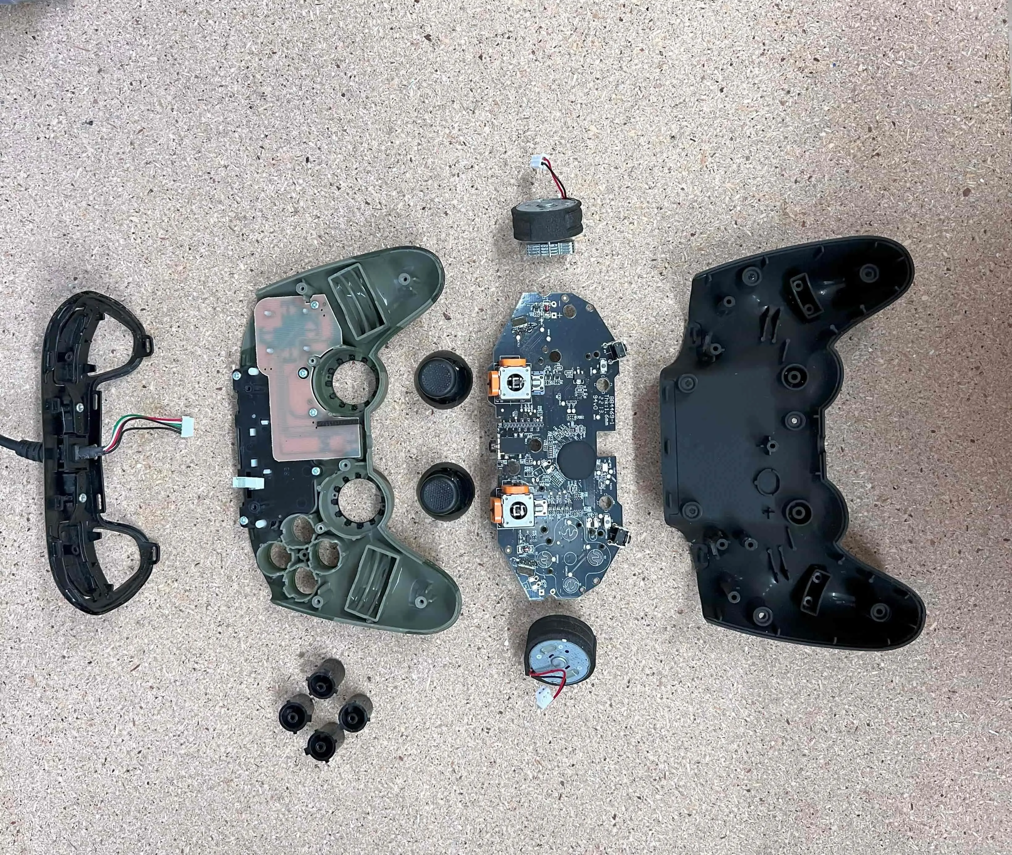 Zerlegter Controller mit Platine und Joysticks auf einer Werkbank
